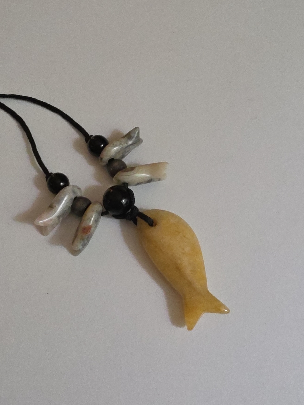 Yellow Stone Fish Pendant Necklace with a Few Smaller Stone Fish On Black Cord